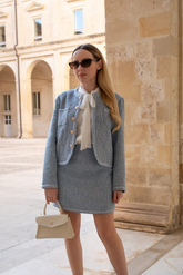 a lady in a white bw tie neck shirt , a blue tweed jacket and a blue tweed skirt